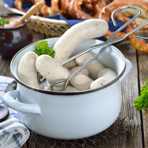 Weißwürste in Topf mit Zange